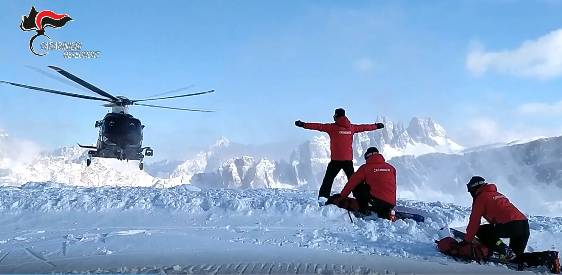 Elicottero in volo su una montagna e Carabinieri impegnati ad effettuare rilievi sulla neve per evitare incidenti provocati da valanghe