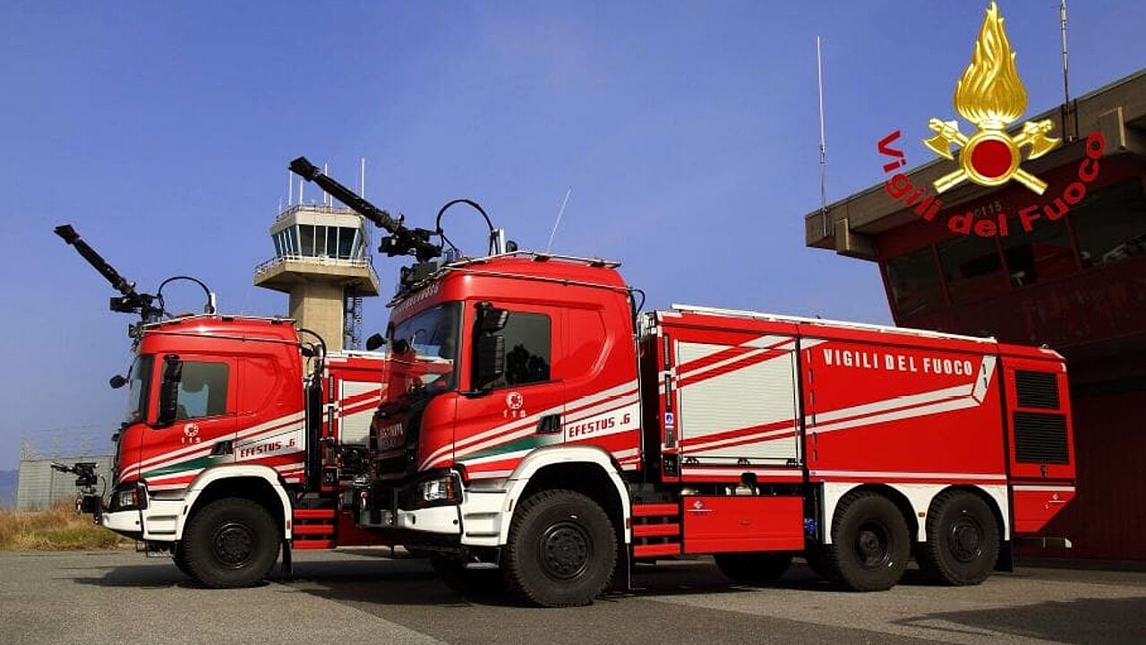 Mezzi antincendio dei Vigili del Fuoco all'ombra della torre di controllo di un aeroporto